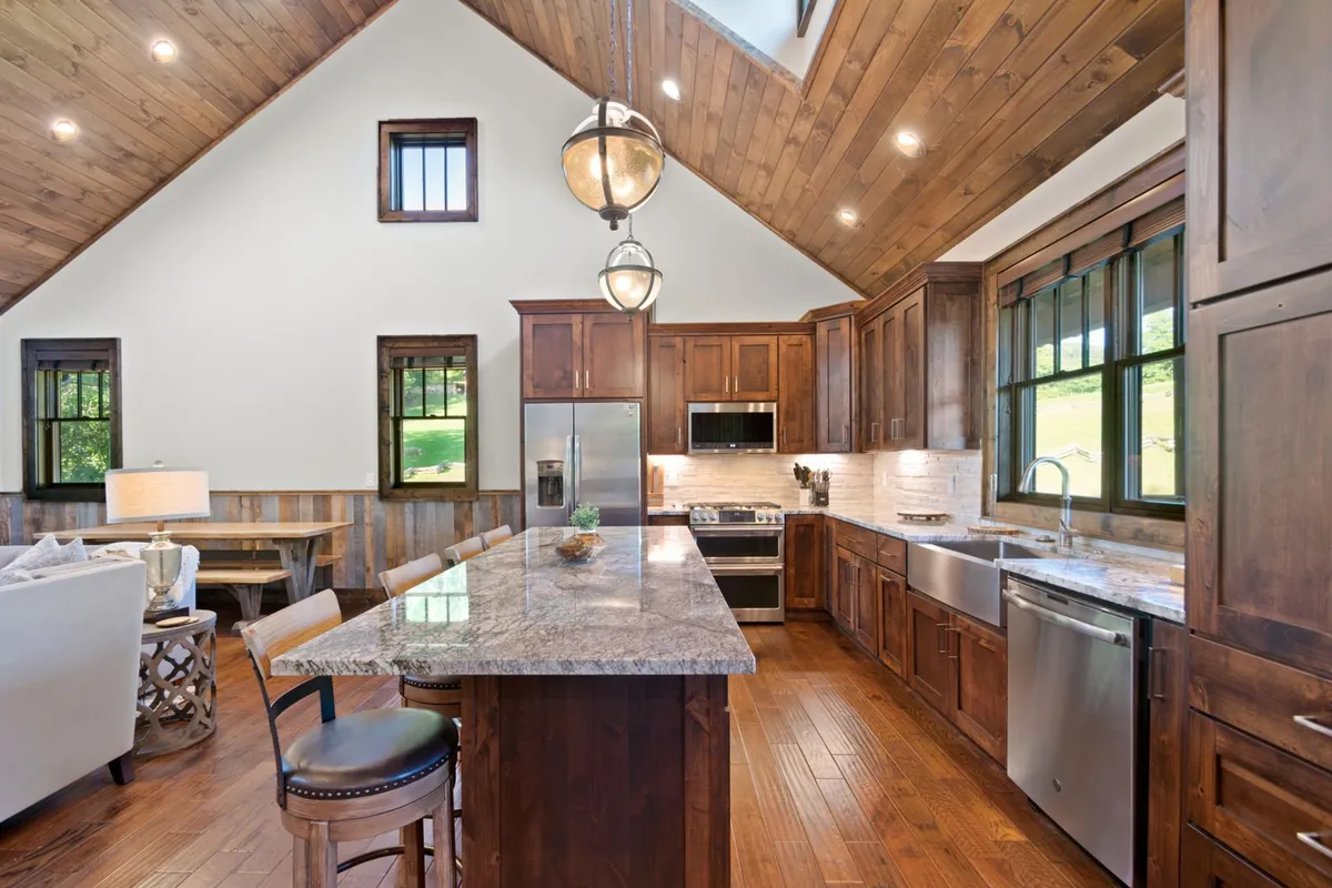 A spacious kitchen with a central island, wooden cabinetry, and large windows letting in natural light. The space is designed for cooking together, entertaining guests, and creating memories around food.