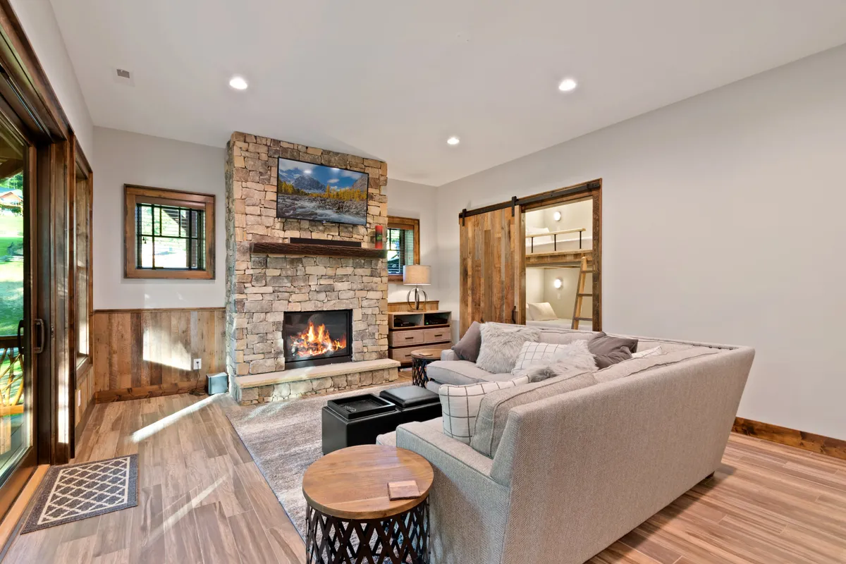 A cozy living room featuring a warm fireplace, plush sofa, wooden accents, and decorative artwork. The space feels inviting and perfect for group gatherings, socializing, or relaxing after a day of exploration.