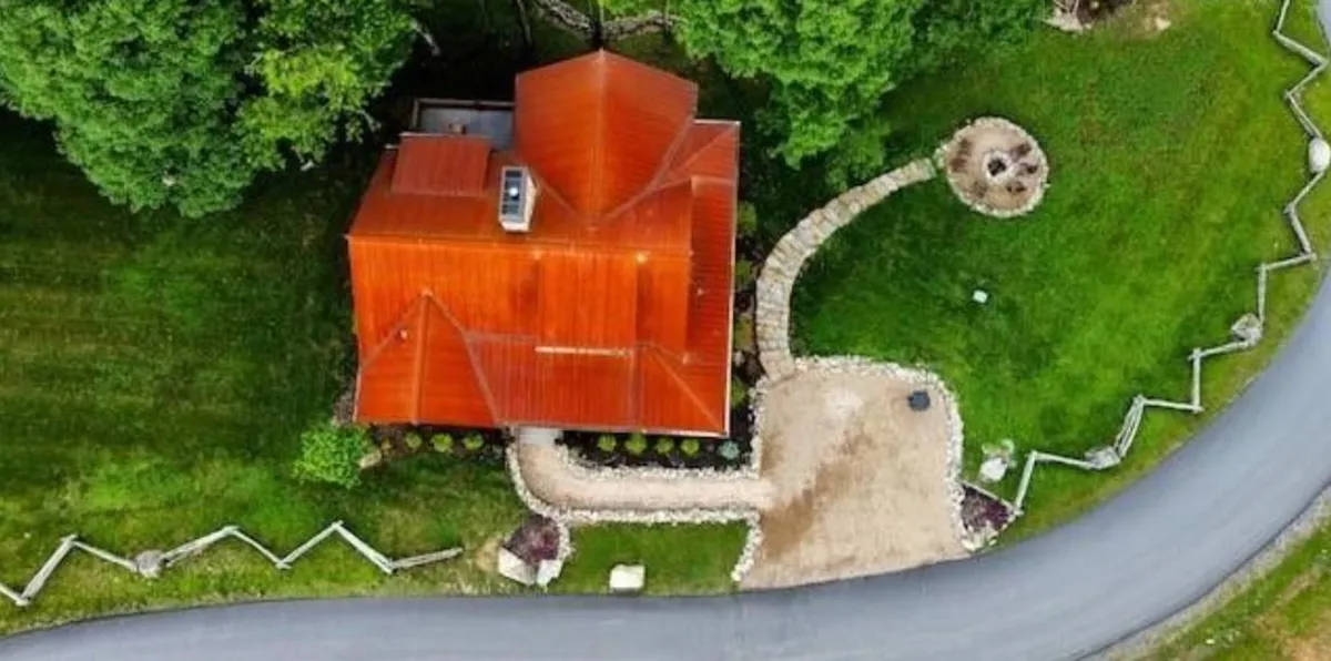 Featuring a front view with a red roof, curved pathway, and lush greenery, this image presents a friendly and inviting exterior. The landscaped yard and outdoor space suggest opportunities for outdoor gatherings and recreation.